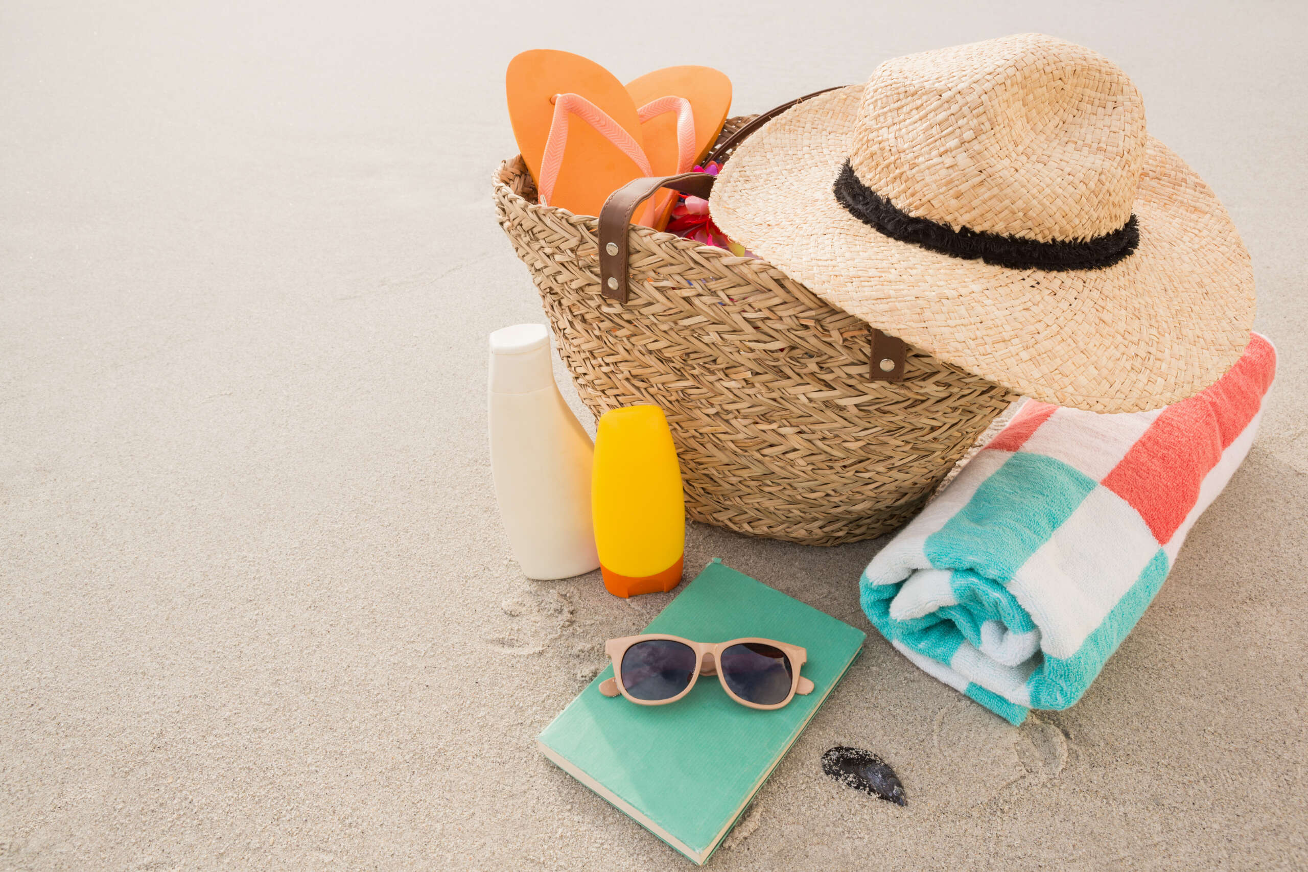 Acessórios na praia como filtro solar, chinelos, ooculos de sol, bolsa de praia