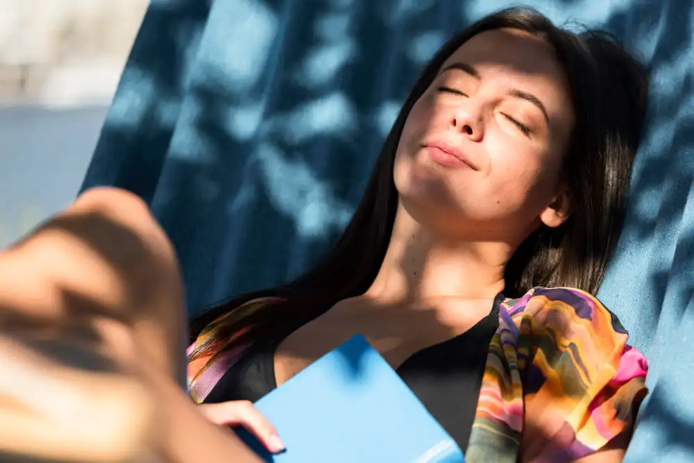 mulher relaxando na sombra para se prevenir dos perigos da exposição em excesso ao sol