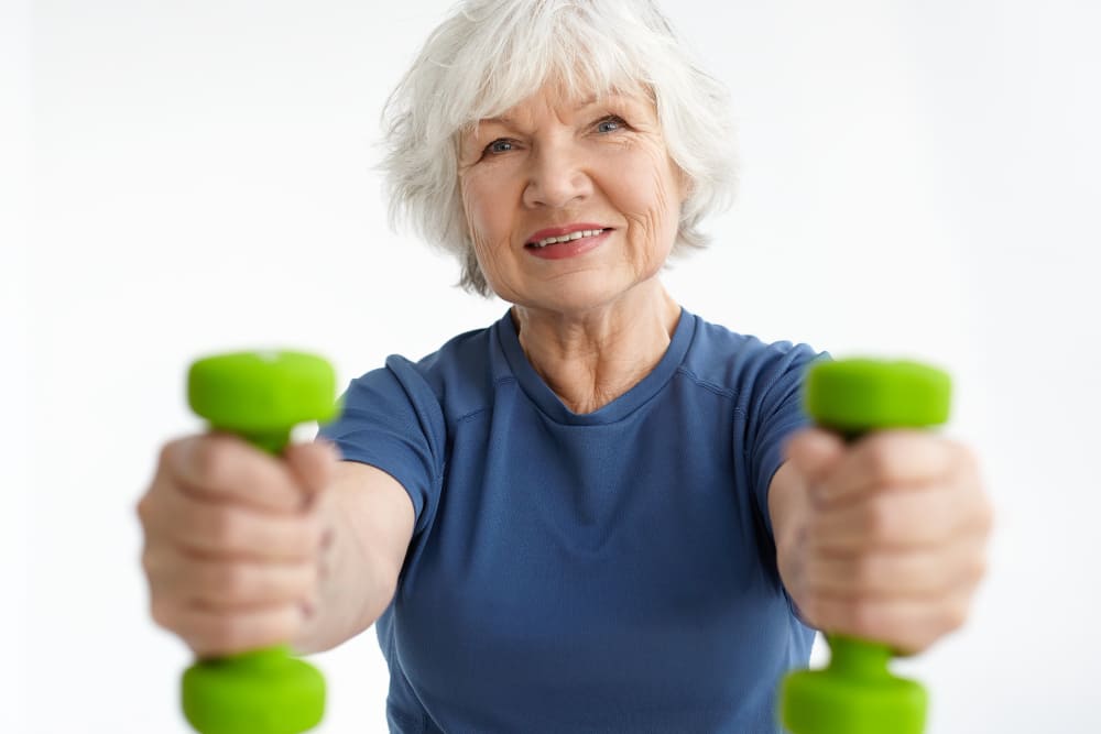 mulher idosa segurando halteres e mantendo os músculos saudáveis na terceira idade